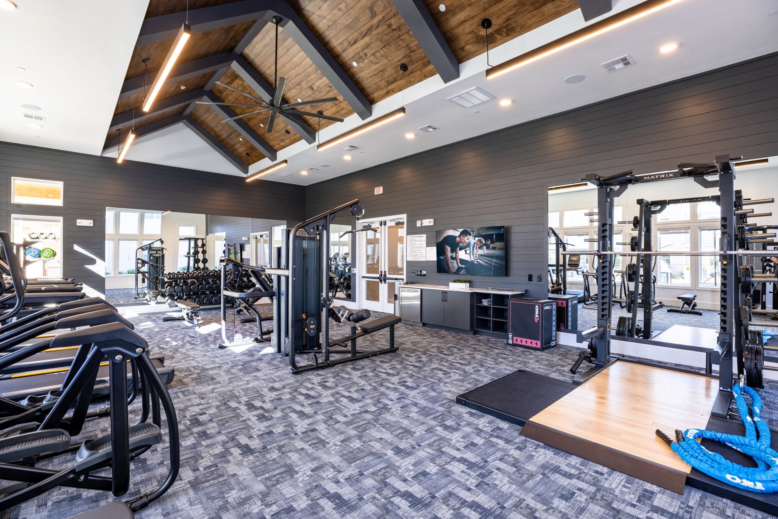 a gym with weights and cardio equipment and a tv on the ceiling